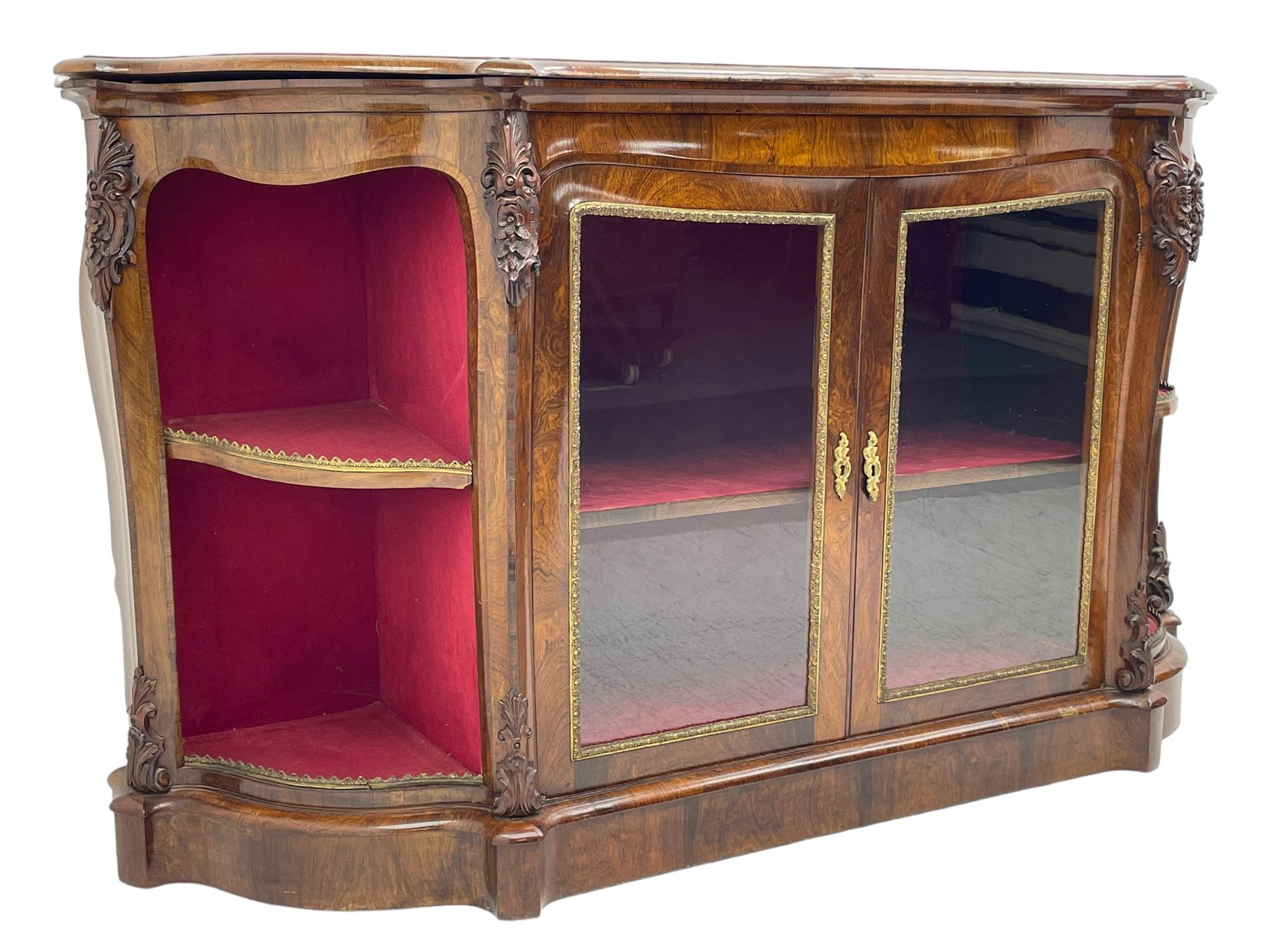 19th century rosewood buffet credenza, bombe form with shaped and moulded top, two central glazed doors with foliate moulded gilt slips, the red fabric-lined interior fitted with a single shelf, flanked by open shelves with raised gilt metal lips, the uprights decorated with shell and flower head carved cartouche mounts, acanthus leaf scroll carved lower mounts, on shaped and moulded plinth base 