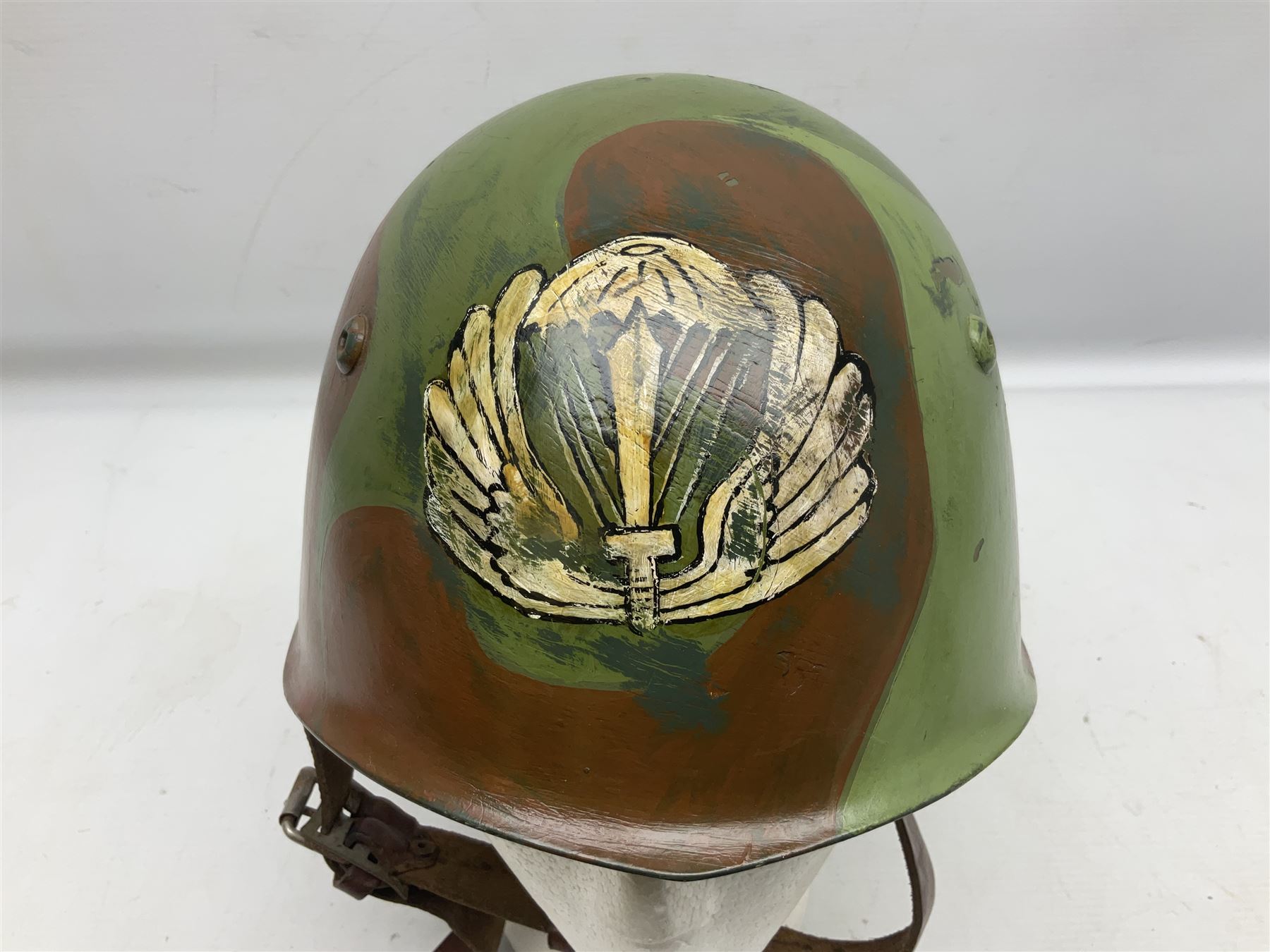 1960s Italian parachutist helmet with liner; camouflage paintwork with parachutist crest to the front