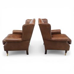 Laura Ashley - Pair of brown leather wingback armchairs, with scrolled arms and loose cushion seat, brass studded trim, on cylindrical tapering legs terminating in castors