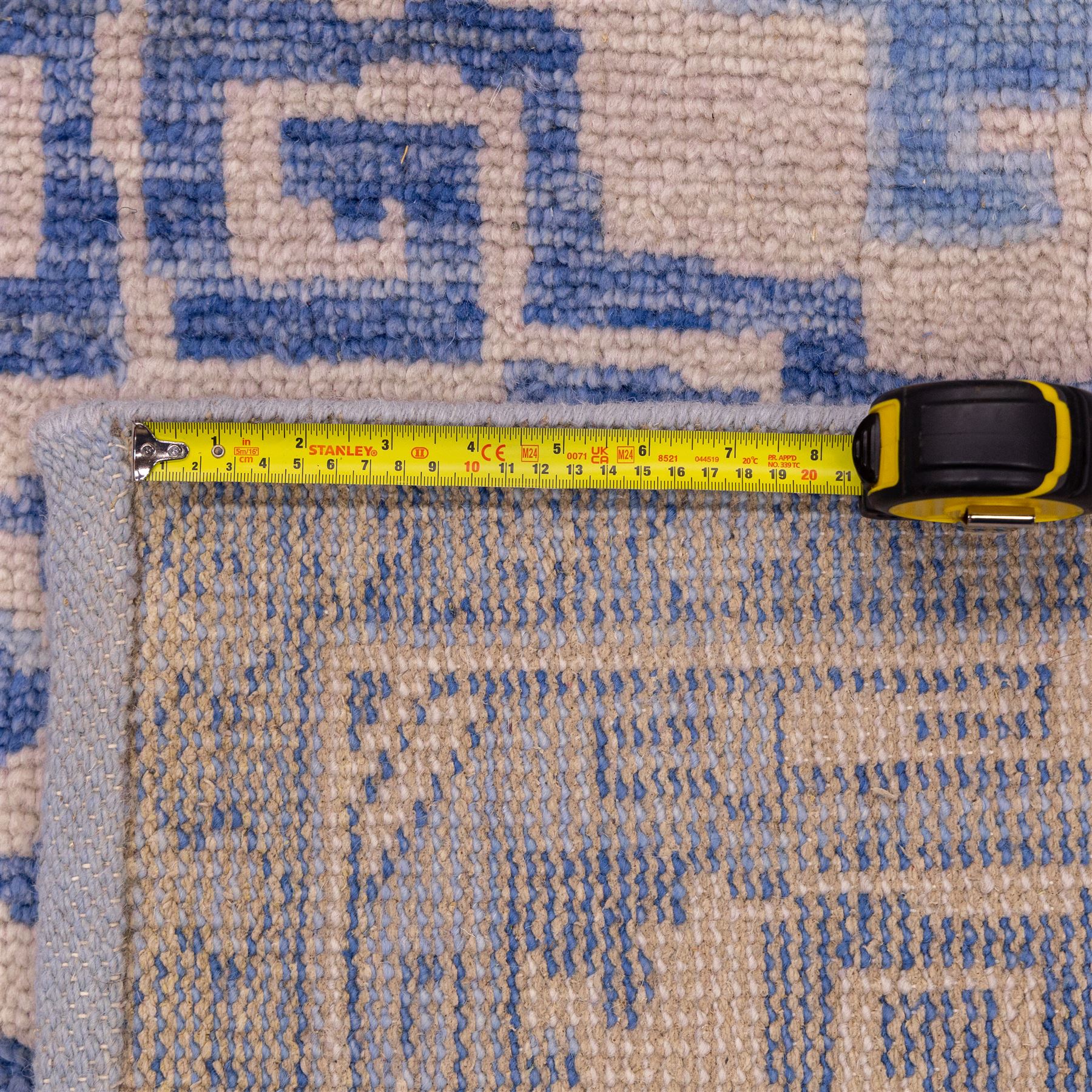 Late 20th century Chinese hand-woven wool carpet, ivory field with a lattice of stylized lotus medallions, contained within geometric key fret panels interspersed with a small floral device enclosed within a complementary Greek-Key border, the designs in tones of pale blue and soft cream