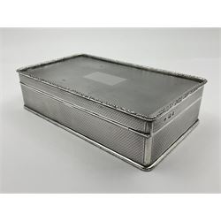 1920's silver table cigarette box, of rectangular form with engine turned decoration to the exterior, the hinged cover with central vacant rectangular panel and raised foliate rim, opening to reveal a gilt interior with later plush lining, hallmarked Charles Henry Dumenil, London 1923, H3.5cm L14.5cm D8.5cm