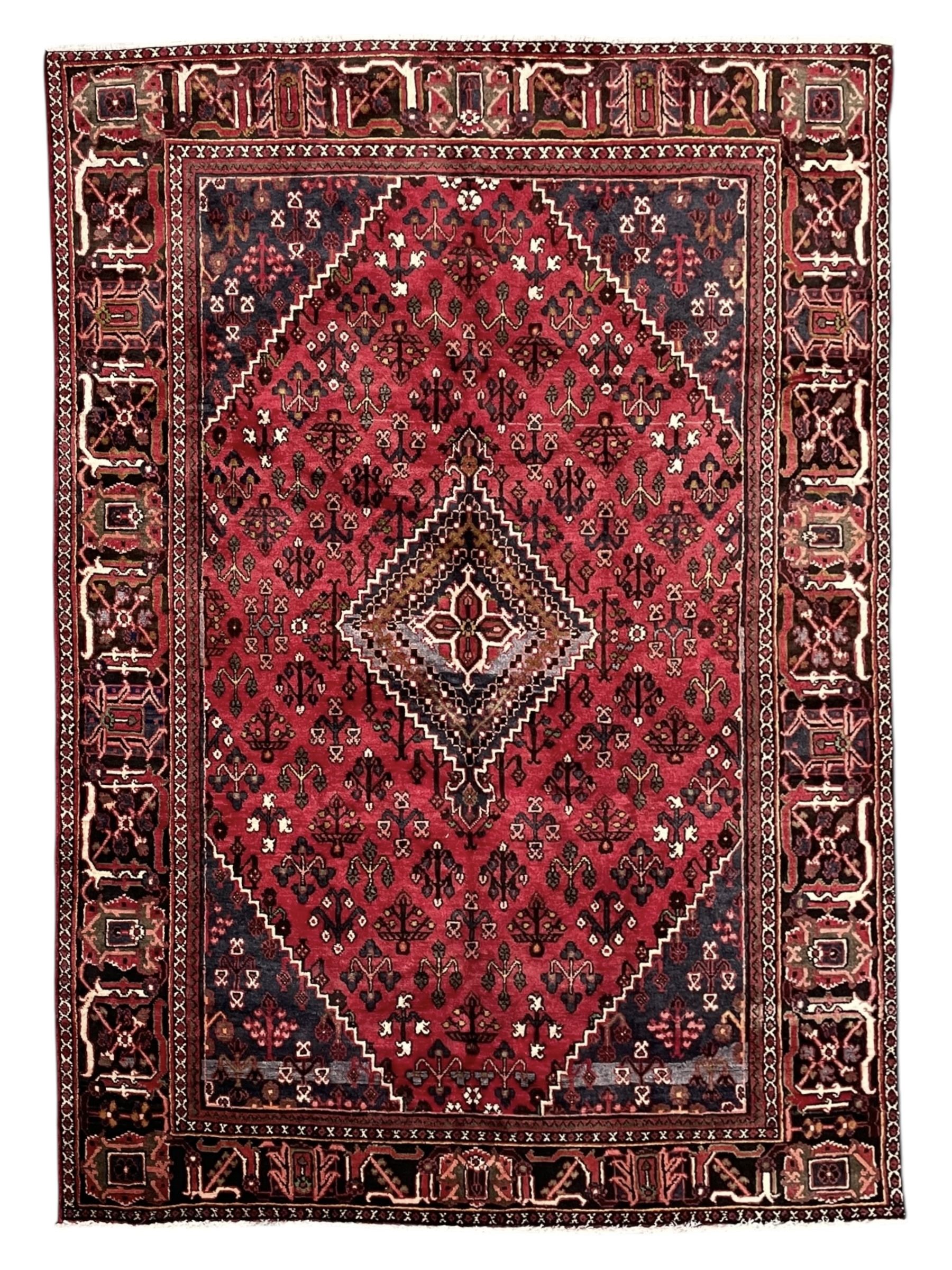 Persian Joshaghan crimson ground rug, stepped lozenge medallion surrounded by repeating foliate lozenge motifs, the border decorated with stylised plant motifs, within geometric guard stripes 