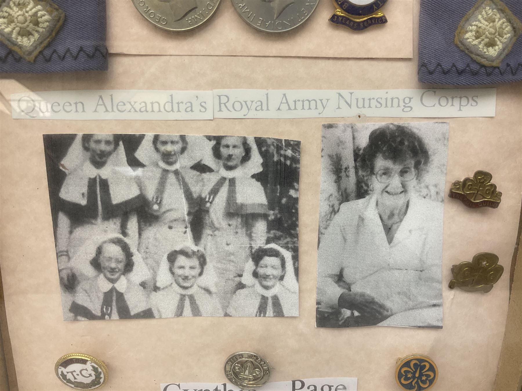 Framed display of medals and badges relating to Captain Cynthia Page of Queen Alexandra's Royal Army Nursing Corps including WW2 War Medal and Defence Medal with miniatures; Red Cross Society 3-Year Service Medal; Q.A.R.A.N.C. cap badge; Girl Guide and silver Scout badges; rank epaulettes; and related photographs 33 x 23cm