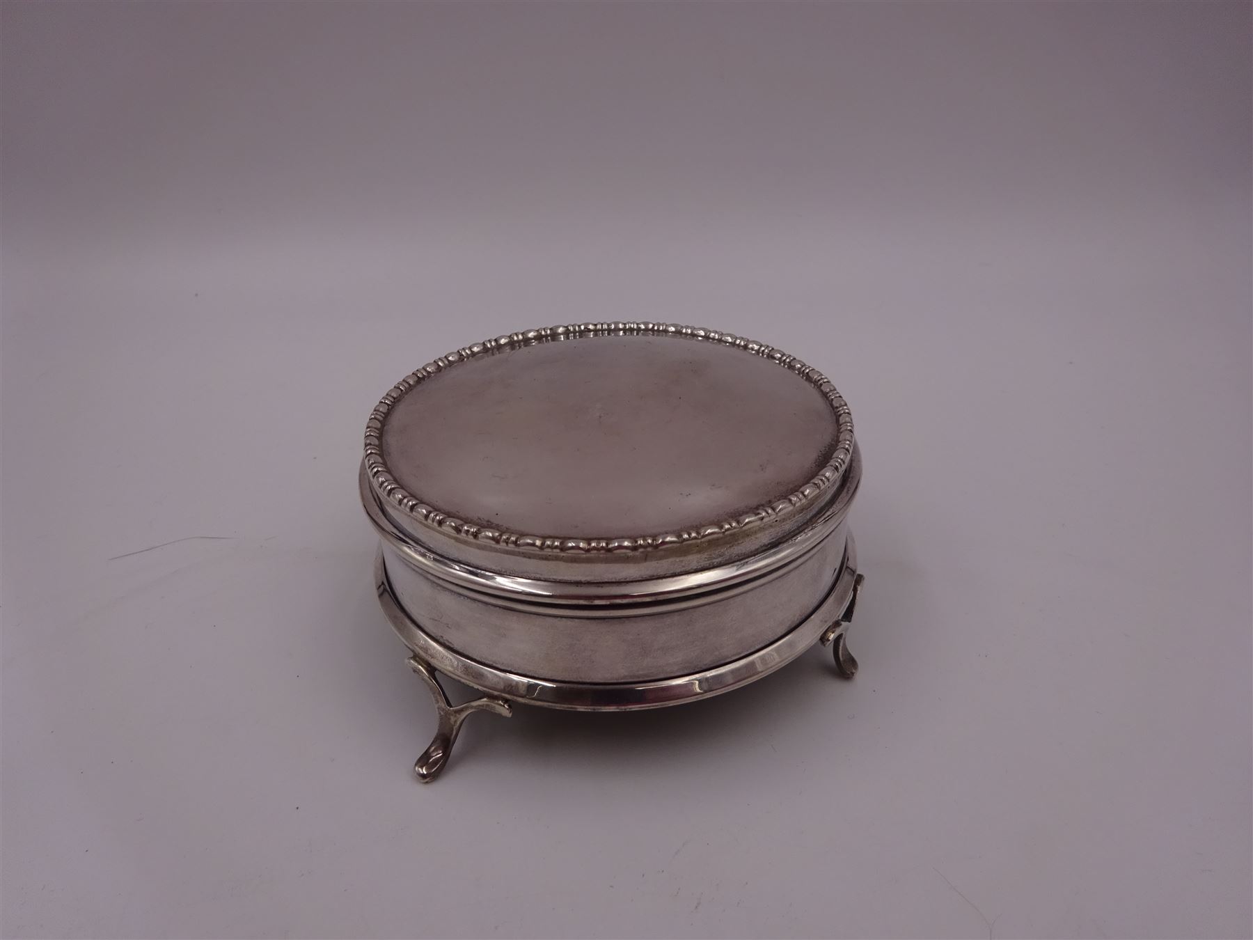 1920s silver mounted jewellery box, of circular form, with bead and dart rim to hinged cover, opening to reveal gilt velvet lined interior, upon four pad feet, hallmarked Charles Edwards, London 1920, H4.5cm