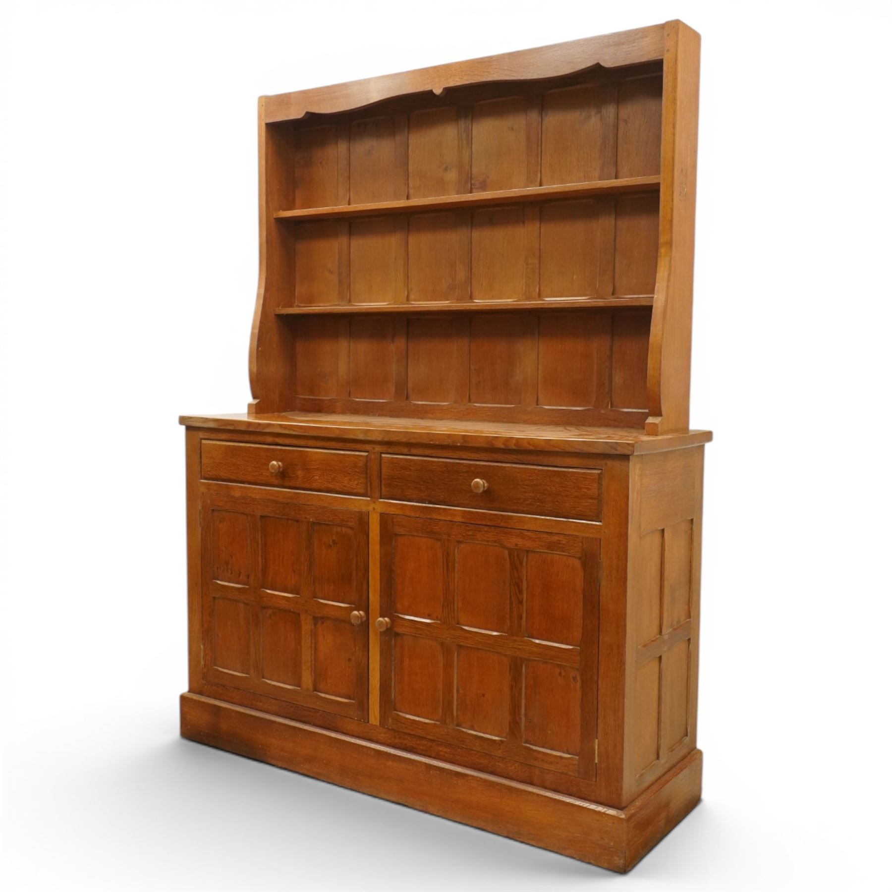 Cat and Mouseman - adzed oak dresser and plate rack, plate rack with two delf rack, panelled back and shaped uprights, above a base with two short drawers and turned wooden handles, panelled cupboard doors and sides, raised on a plinth base, with carved Cat and Mouseman signature, by Lyndon Hammell of Harmby