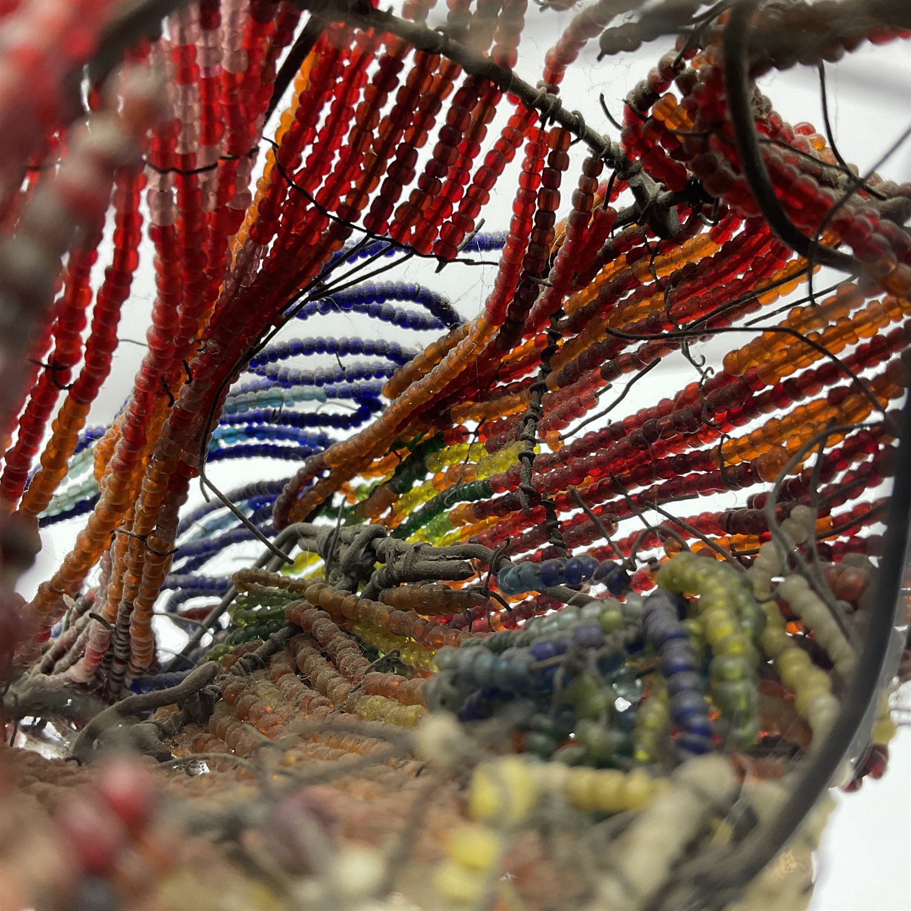 Victorian bead and wire model of a parrot, of polychrome beads, with glass eyes, on a wooden base, H24cm