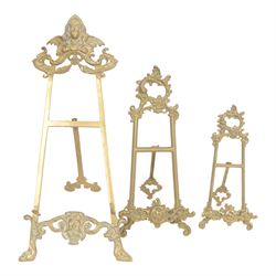 Three Baroque design brass table easels, the largest with cast mask detail, H47cm, and two...