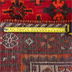 South West Persian Lori hand-knotted rug,  deep crimson field with a stepped lozenge medallion enclosing stylised floral motifs within multiple geometric borders of indigo, ivory, and green, with fringe ends 