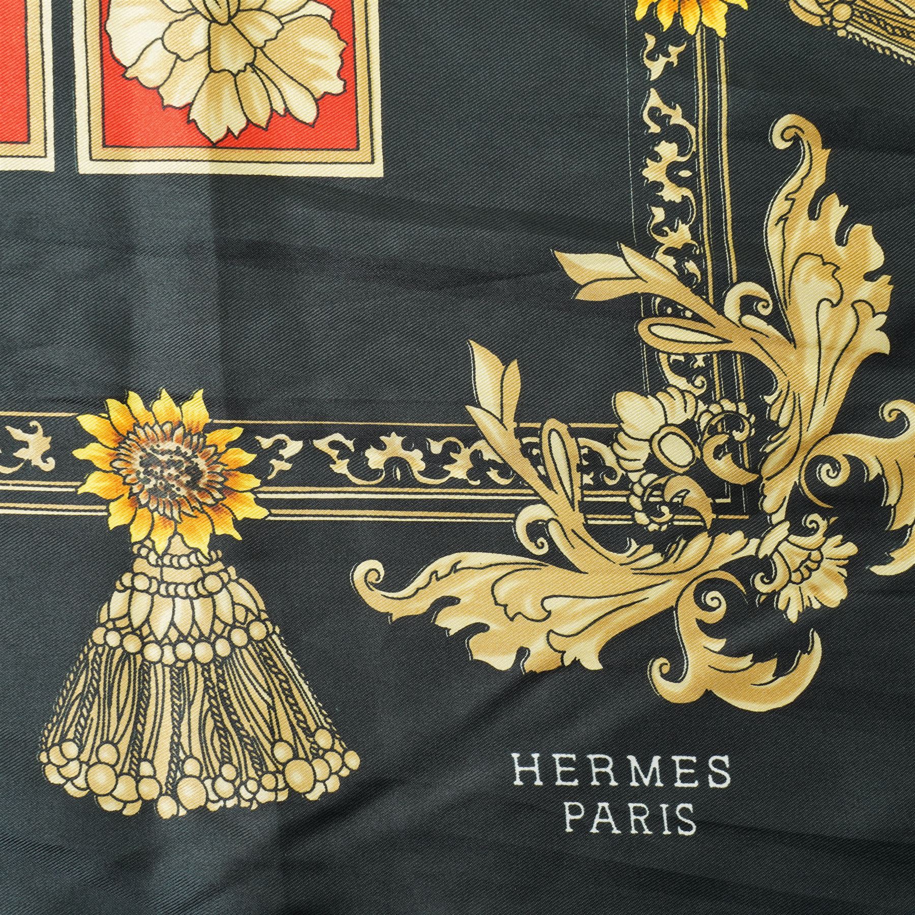 Hermès silk carré scarf, the black ground with central sunflower motif framed by ornate baroque panels and tassel borders in red, gold and yellow tones, signed Hermès Paris to the corner, hand-rolled edges, 90cm x 90cm