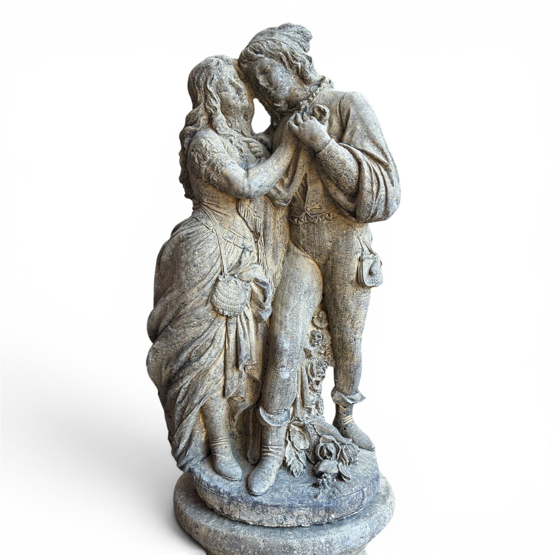 Composite garden statue group of Romeo and Juliet embracing, the couple adorned in Medieval dress standing on a naturalistic base with fallen flowers, raised on a Neoclassical fluted pedestal with Anthemion leaf motifs