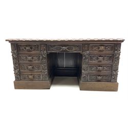Victorian heavily carved oak twin pedestal desk, the rectangular top with lunette carved edge and inset leather writing surface, nine drawers each carved with leaves and cartouche handles, on plinth base