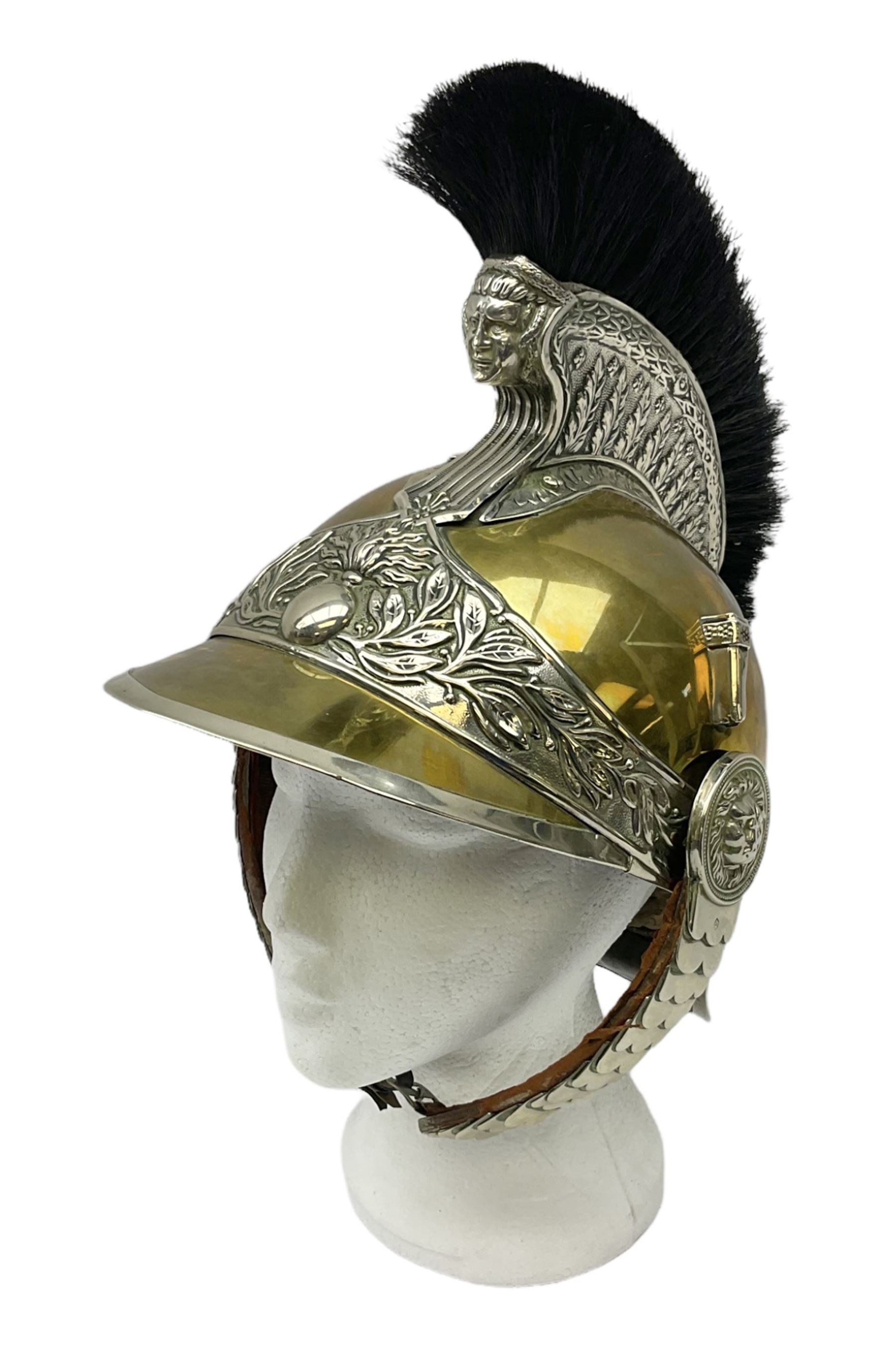 Early 20th century French mounted gendarme's helmet, brass with nickel-silver mountings, broad band embossed with fused grenade, high comb with the face of the gorgon Medusa at the peak and with a black horse hair crest, plume socket at the left, leather-backed nickel-silver chin scales with lion mask mounts.