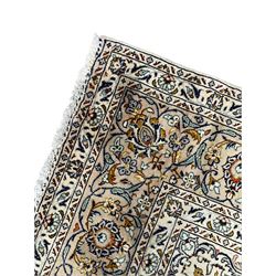 Persian Kashan ivory ground carpet, central pole medallion surrounded by swirling leafy branches and stylised plant motifs, scrolled foliate spandrels, the main border decorated with scrolling pattern and repeating palmettes, within floral patter guard stripes 
