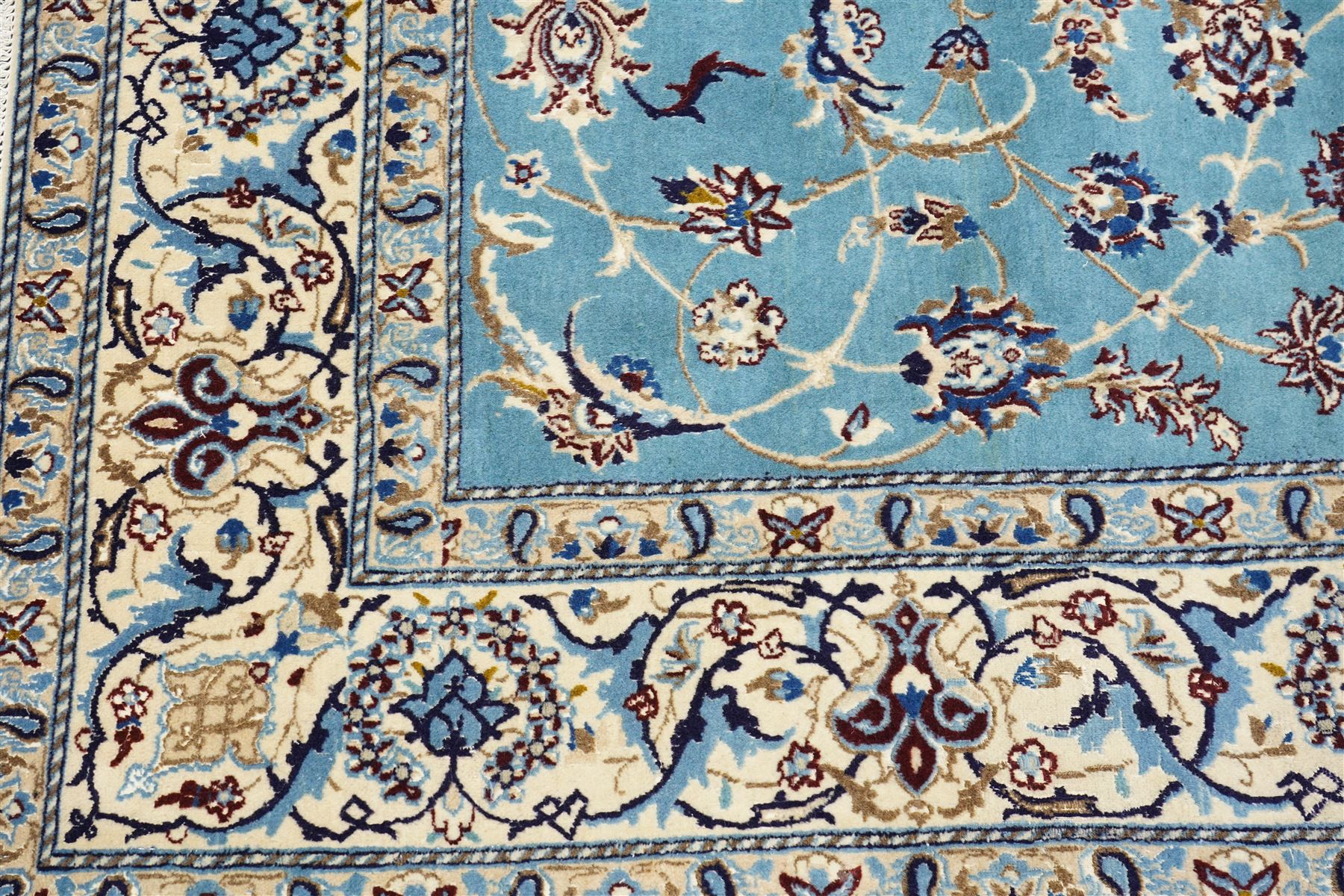 Central Persian Nain hand-knotted carpet, soft sky blue ground with central cusped medallion of radiating palmette form, issuing scrolling vine work, arabesques, and delicate floral sprays, spandrels of conforming design, main border of ivory ground decorated with scrolling vine work palmettes and stylized floral motifs, flanked by narrow guard stripes, with cotton fringe ends 