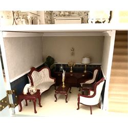 Georgian style wooden double fronted three-storey dolls house with pale blue stucco finish under a faux tiled roof with two chimney stacks, the double hinged front opening to reveal six fully decorated rooms with floor coverings, central staircase, porcelain fitted bathroom, kitchen with deep white sink and Aga cooker, electric lighting with adaptor, fully furnished with French style and other furniture, grand piano etc, and comprehensive range of accessories H82cm W61cm D31cm