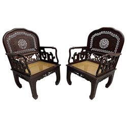 Pair of late 19th century Chinese hardwood armchairs, the pierced and carved back decorated with a central shou motif below a stylised carved bat with a surrounding pierced roundel band, over a cane seat, the apron carved with dragons flanking a floral symbol, the inward swept supports decorated with scrolling foliage