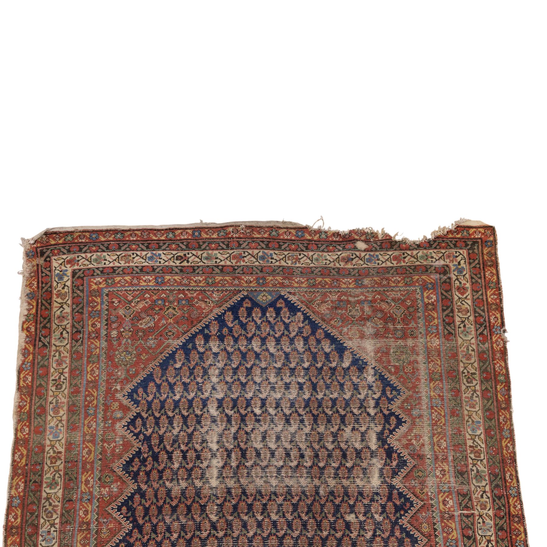 West Persian Kurdish vintage carpet, indigo field decorated with an all-over repeating boteh design arranged in diagonal rows framed by angular spandrels and enclosed by multiple geometric borders in a palette of indigo blue, madder red, soft green and ivory