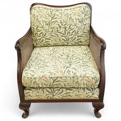 Edwardian stained beech Bergère armchair, with double cane sides and back, with the apron seat and cushion seat and back cushion, upholstered in a William Morris Willow Bough fabric, supported on cabriole legs with pad feet 