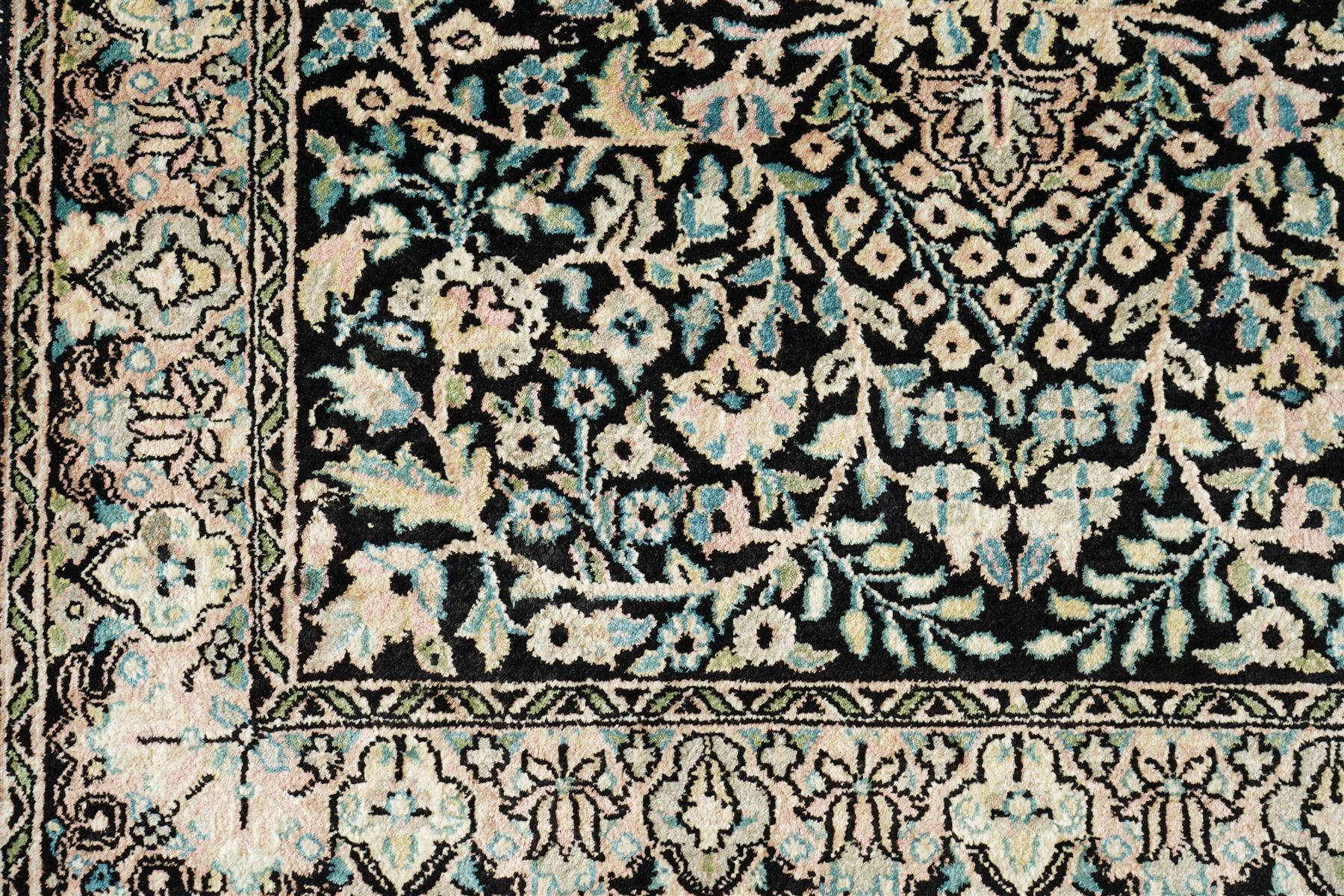 Persian style rug, central floral medallion surrounded by intricate palmetters, vines and rosettes, navy blue ground with ivory and pink highlights