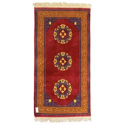 Tibetan-design handwoven rug, deep red field with three central medallions in yellow and blue, traditional yellow key border, white fringes on both ends