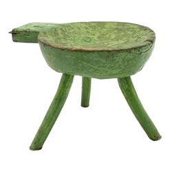 18th/19th century vernacular primitive green painted stool with dished seat fitted with metal scraper to one end, on three splayed legs, L46cm, H34cm