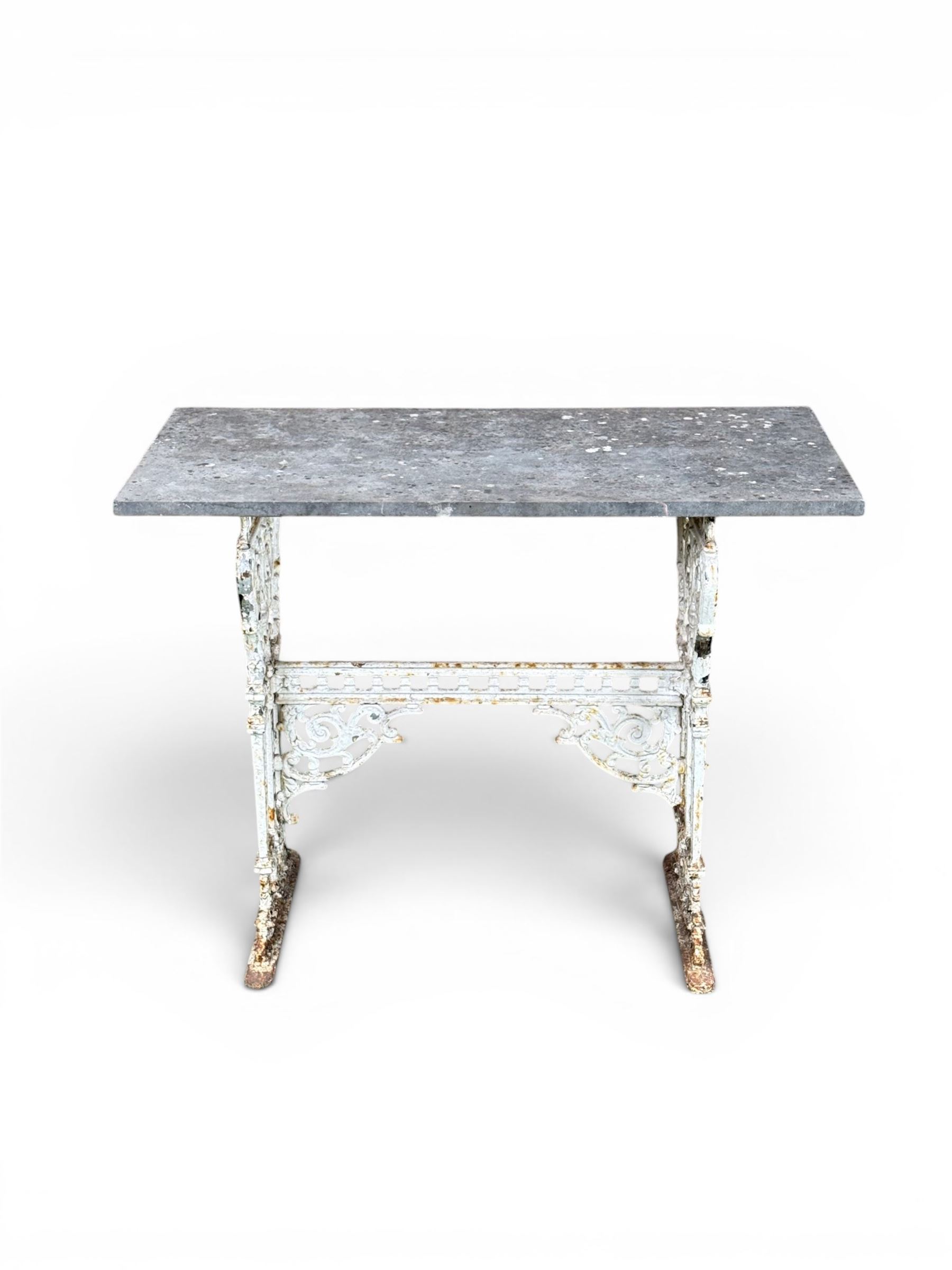 Victorian cast iron garden table, rectangular slate top raised on pierced scrolling foliate end supports with urn and column designs, united by a spindle support stretcher with scrolling acanthus spandrels, stamped 'Registered Design' with indistinct number, in distressed white painted finish