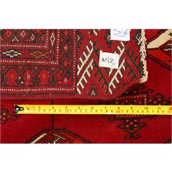 Turkmen hand-knotted carpet, deep crimson ground field, with an all-over lattice of repeating diamond guls, each enclosing angular cruiform motifs, and stylized tribal devices, interspersed with smaller geometric ornaments, main border decorated with repeating geometric motifs and stylized tribal elements, flanked by narrow guard stripes, with cotton fringe ends 