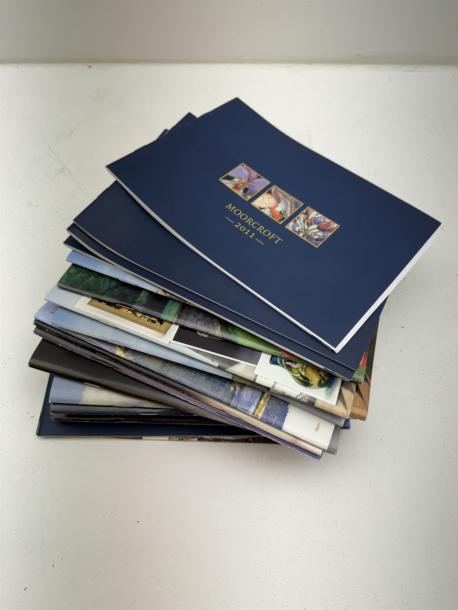 Three Moorcroft reference books, comprising Winds of Change, The Phoenix Years and A New Dawn, together with a collection of Moorcroft magazines 