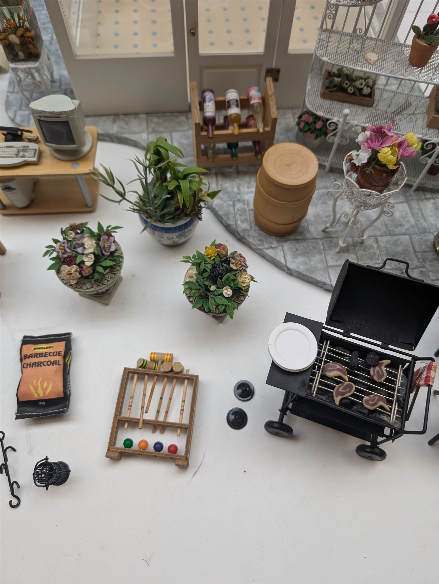1:12 scale dolls house conservatory and garden accessories, including white wooden glazed conservatory on a stone effect base, black and white metal garden seating, barbecue, plant shelves, parasol, barbeque accessories, large planters, rabbit hutch, animals, chimenea, etc