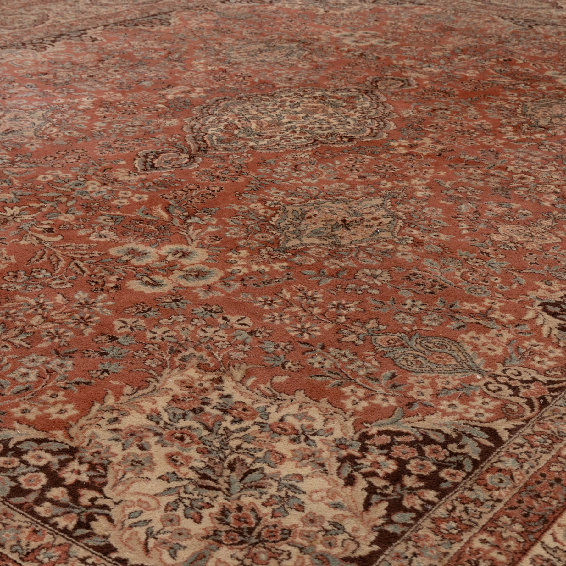 Persian vermillion ground Kashan rug, the busy field decorated with a central floral pole medallion, surrounded by trailing foliage and profusely woven floral patterns and bouquets, the dark indigo spandrels and multiple guard bands with similar floral decoration and stylised spandrels