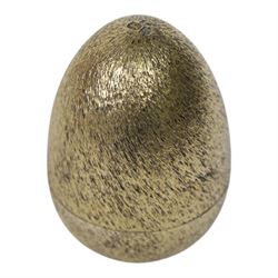 Late 20th century silver and silver-gilt surprise egg, the textured gilt exterior opening to reveal a clutch of chicks, the clustered heads supported upon a spring, within a jagged and lobed silver and gilt encasement, with green enamel surround, hallmarked Stuart Devlin, London 1982, H7cm