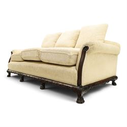 Quality Edwardian carved mahogany lounge suite comprising three-seater settee and pair of armchairs, the sofa with arched back over rolled arms and deep sprung seat, the arm terminals carved with acanthus rosette over gadroon and rope-twist moulding, the shaped apron carved and moulded with scrolling foliate acanthus motifs, terminating to four large front hairy paw and ball feet, upholstered in pale yellow foliate fabric with matching seat and scatter cushions (W200cm D105cm H73cm); the matching deep armchairs (W78cm D95cm H75cm)