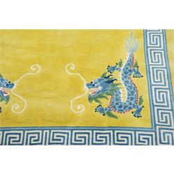 Modern Chinese hand-knotted wool pile carpet, golden field decorated with conforming dragons amidst stylized cloud scrolls enclosed by a Greek gey meander border, with cotton fringe ends 