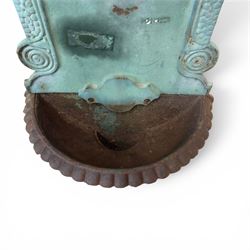 Antique cast iron wall fountain, cartouche cresting rail over a lion mask spout, with scroll and floral decoration over a scalloped basin, in rustic turquoise painted finish with rusted patina