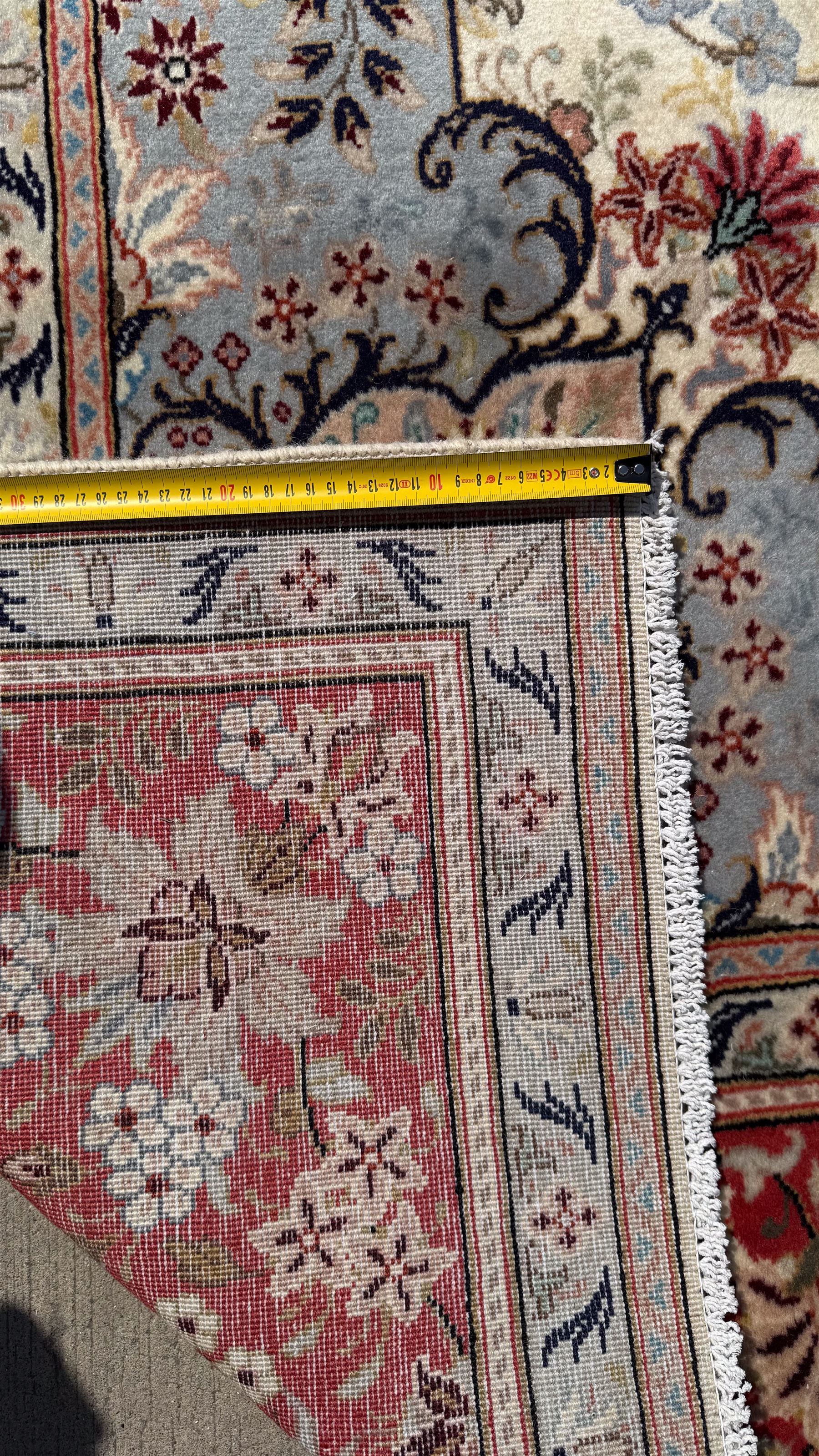 Central Persian Kashan rug, ivory and teal ground, overall geometric design, angular interlaced decorated field with stylised plant motifs, crimson ground, central medallion, the crimson main border band decorated with geometric motifs