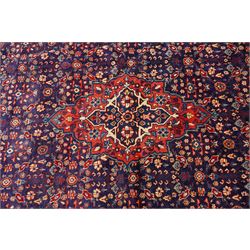 West Persian Mahal hand-knotted carpet, indigo field with central stylized angular medallion issuing an all-over Herati-inspired lattice of floral sprays, rosettes and geometric vinery in tone soft madder red, ivory and soft blue, principal border decorated with stylized palmettes, and angular vine motifs, flanked by multiple guard borders, with cotton fringe ends 