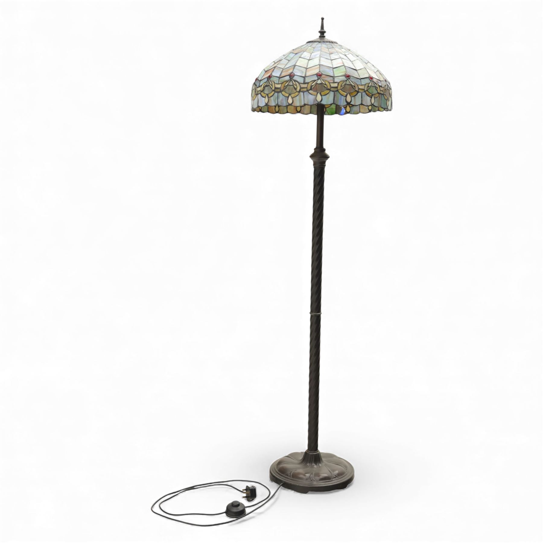 Late 20th century Tiffany style standard lamp, the leaded glass domed shade composed of geometric panels in mottled pastel tones, bordered by stylised foliate motifs and coloured cabochons, raised on a spiral twist metal column and circular moulded base