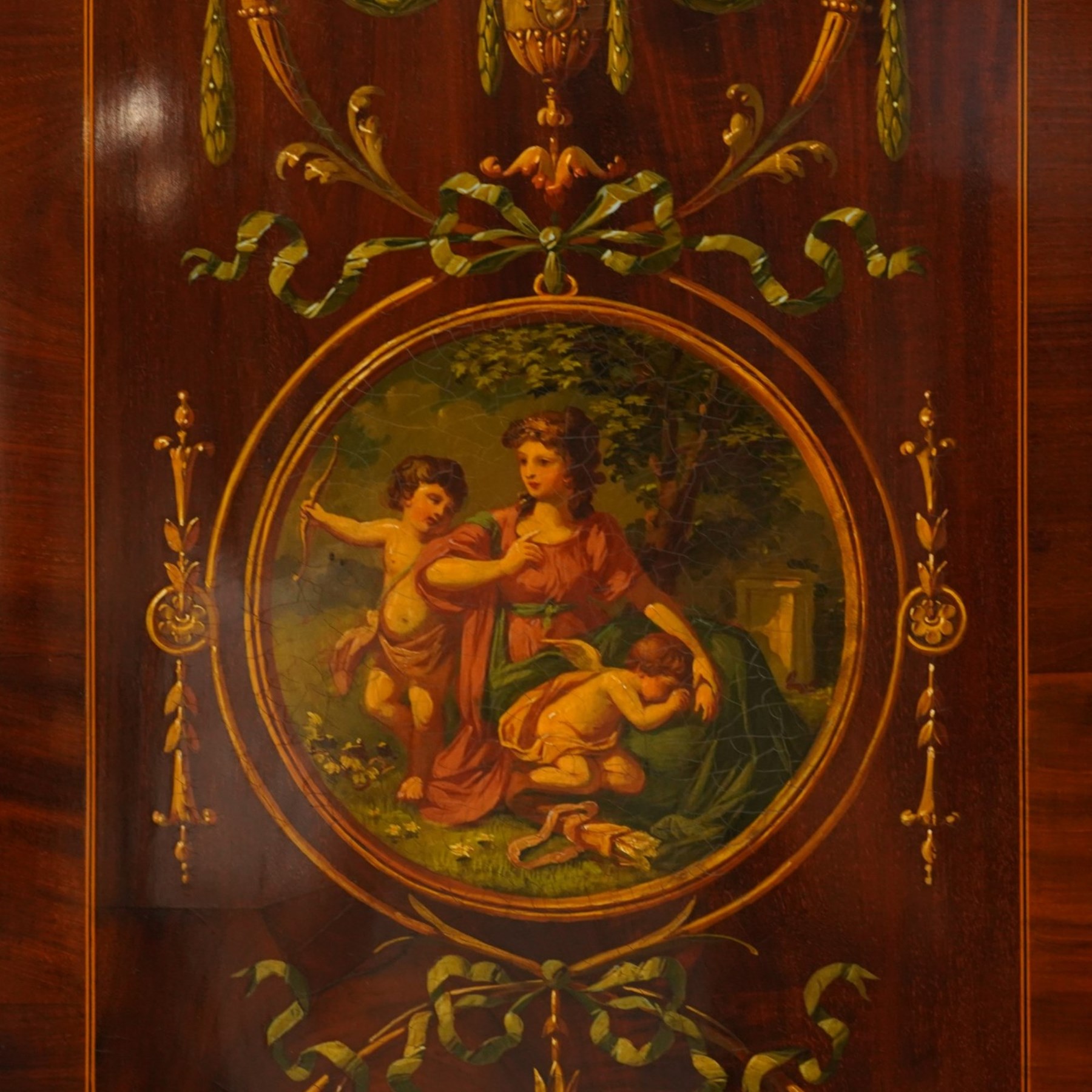19th century French Louis XVI design mahogany and polychrome painted gentleman's press wardrobe - projecting cavetto cornice with urn and bellflower painted frieze, the twin doors with classical figural medallions surmounted by urns and festoon decoration with scrolling acanthus leaves, enclosing five sliding trays, the base fitted with two short over three long cock-beaded drawers, the facias painted with interlocking swags and garlands of bouquets with recumbent lion brass handle-plates, lower reeded edge on turned feet
