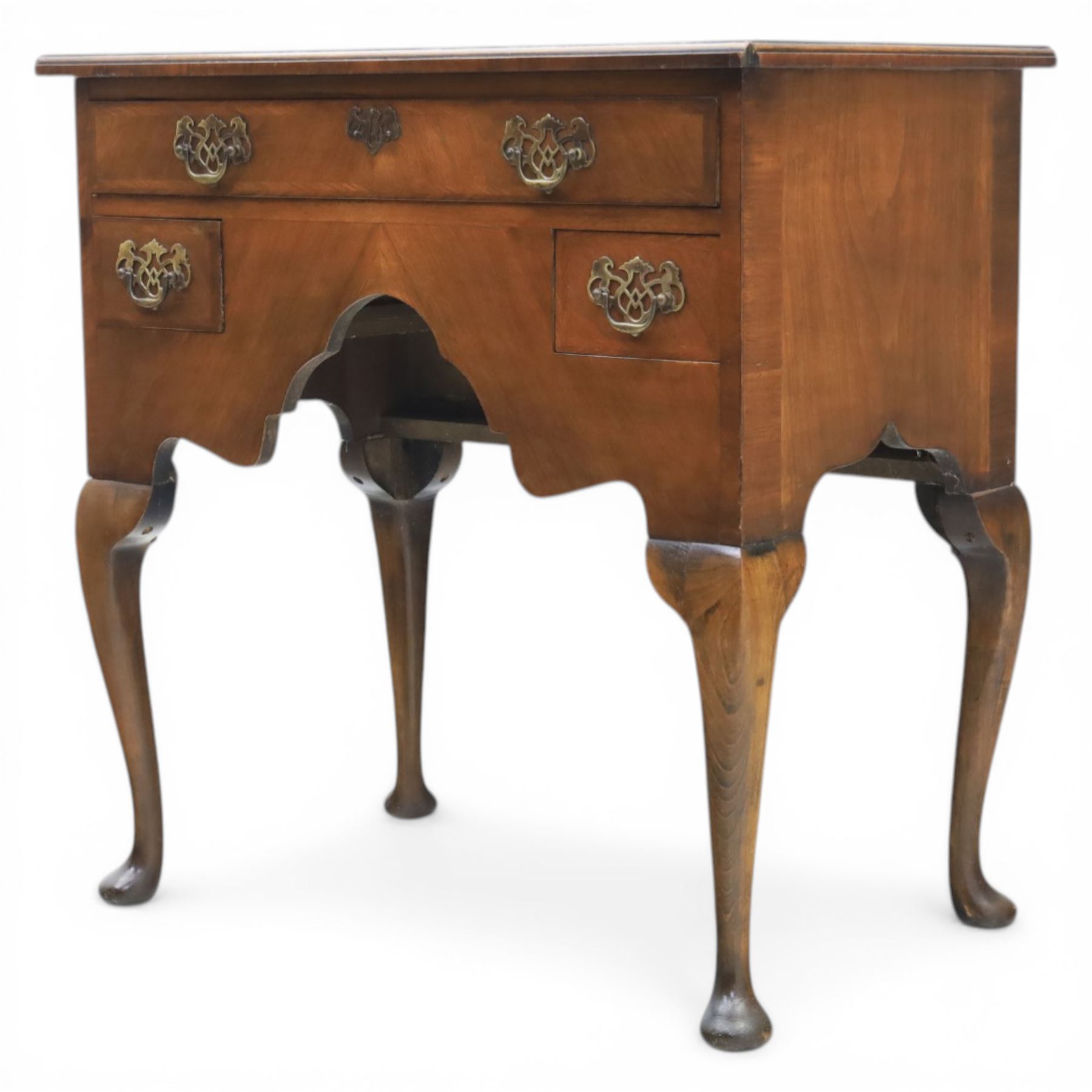 Early 20th century walnut lowboy in Queen Anne style, rectangular crossbanded top over single long drawer and two short drawers with shaped apron, fitted with brass drop handles and backplates, raised on cabriole supports terminating in pad feet