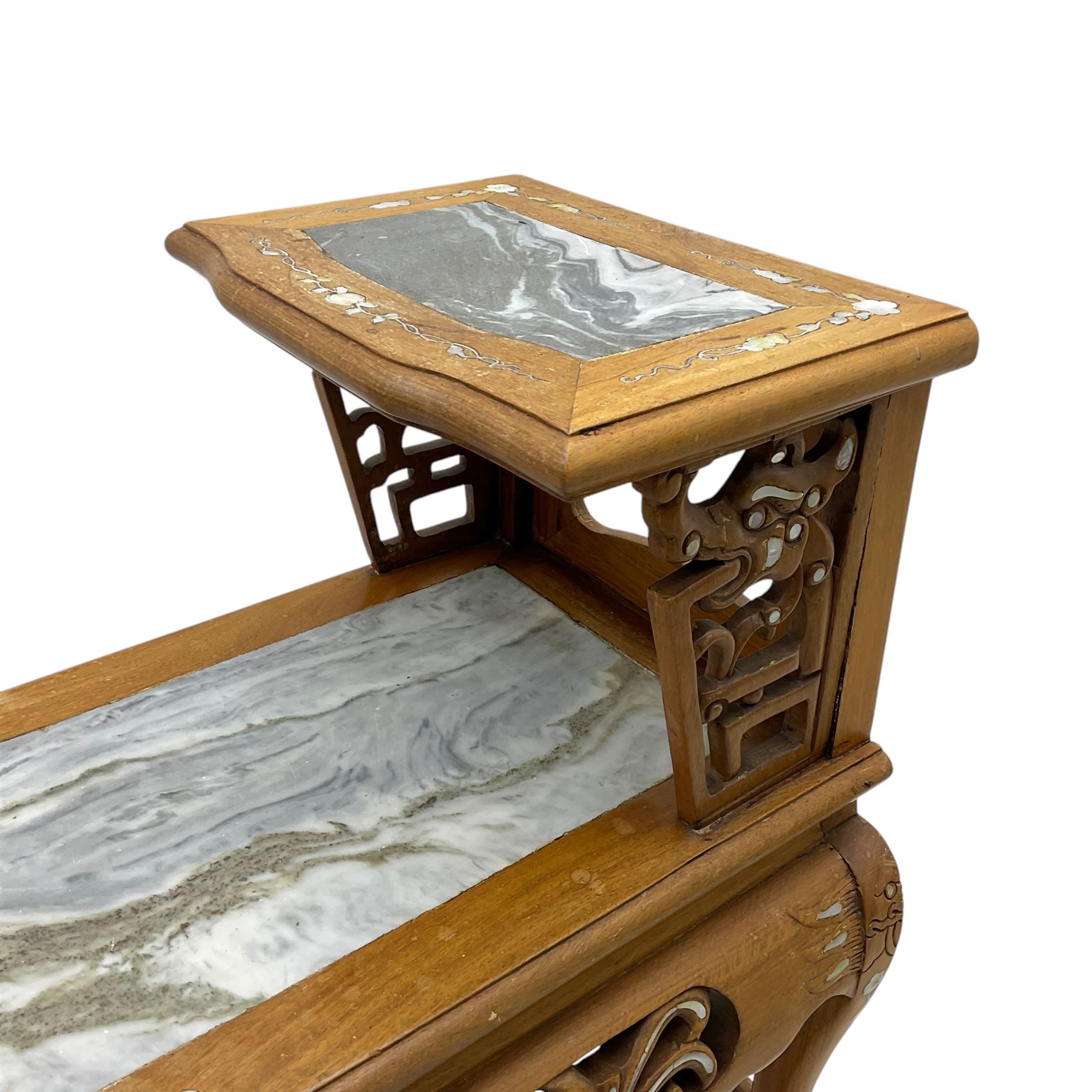 Pair of Chinese hardwood side or end tables, two moulded tiers with grey marble insets, inlaid with trailing foliate motifs in mother of pearl, with scrolling fretwork frieze rails, on cabriole supports with ball and claw feet united by plain stretchers 