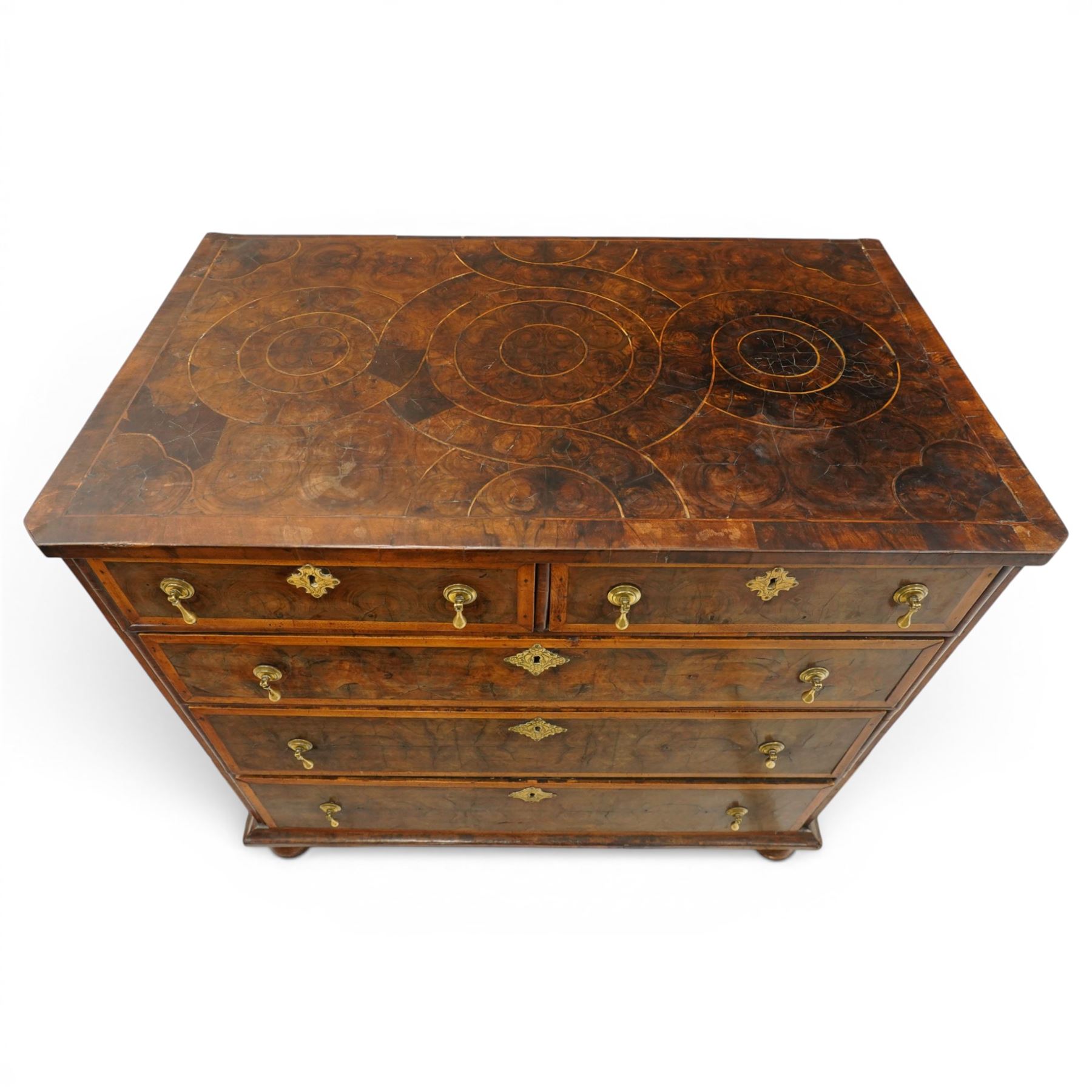 William & Mary period laburnum and walnut oyster-veneered chest, the rectangular top with canted corners and walnut banded edge, profusely decorated with oyster veneer and fruitwood stringing in concentric circles, fitted with two short over three long drawers with fruitwood banding, each fitted with original pressed brass escutcheons and pull handles, lower moulded edge over original bun feet