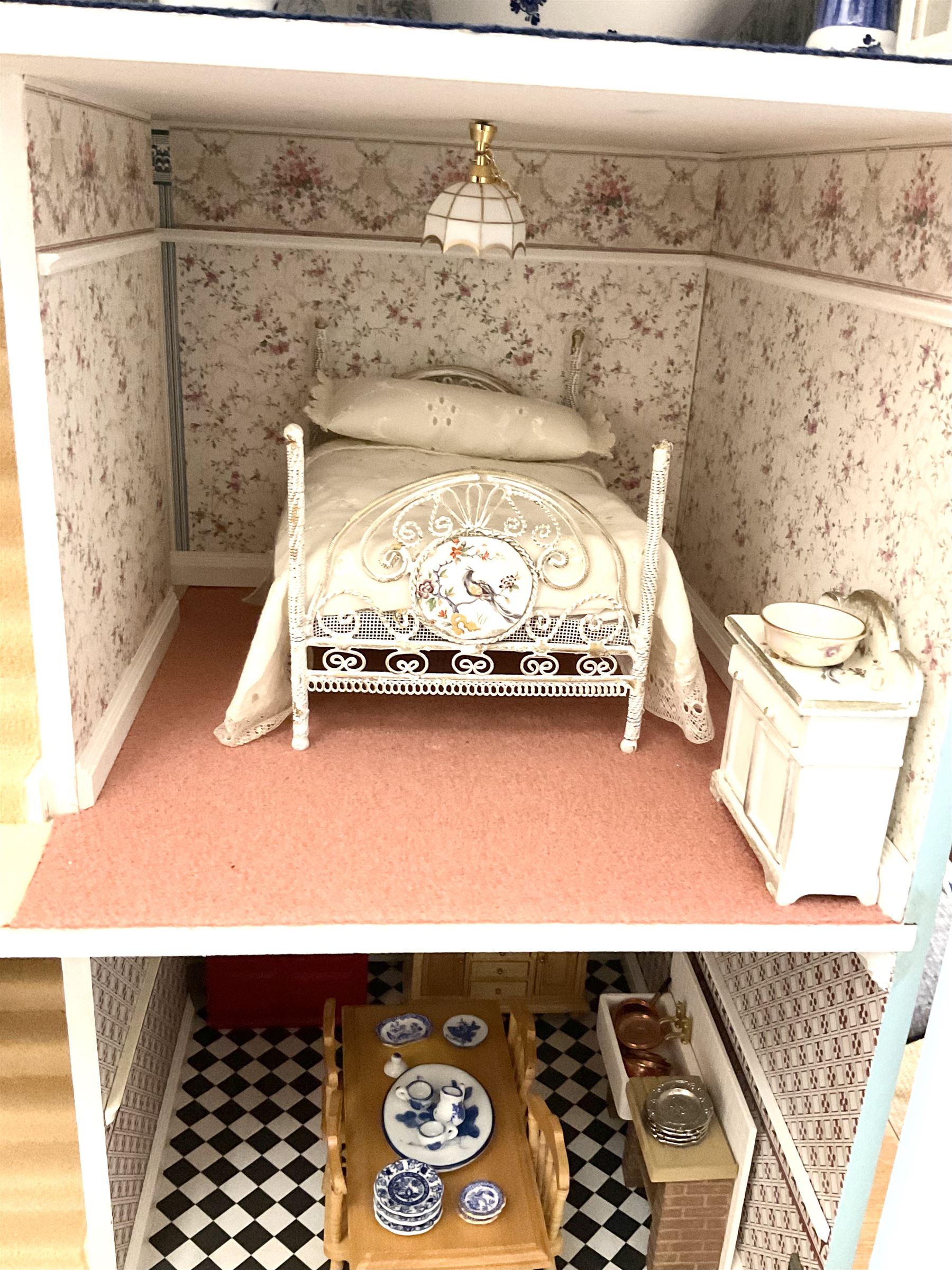 Georgian style wooden double fronted three-storey dolls house with pale blue stucco finish under a faux tiled roof with two chimney stacks, the double hinged front opening to reveal six fully decorated rooms with floor coverings, central staircase, porcelain fitted bathroom, kitchen with deep white sink and Aga cooker, electric lighting with adaptor, fully furnished with French style and other furniture, grand piano etc, and comprehensive range of accessories H82cm W61cm D31cm