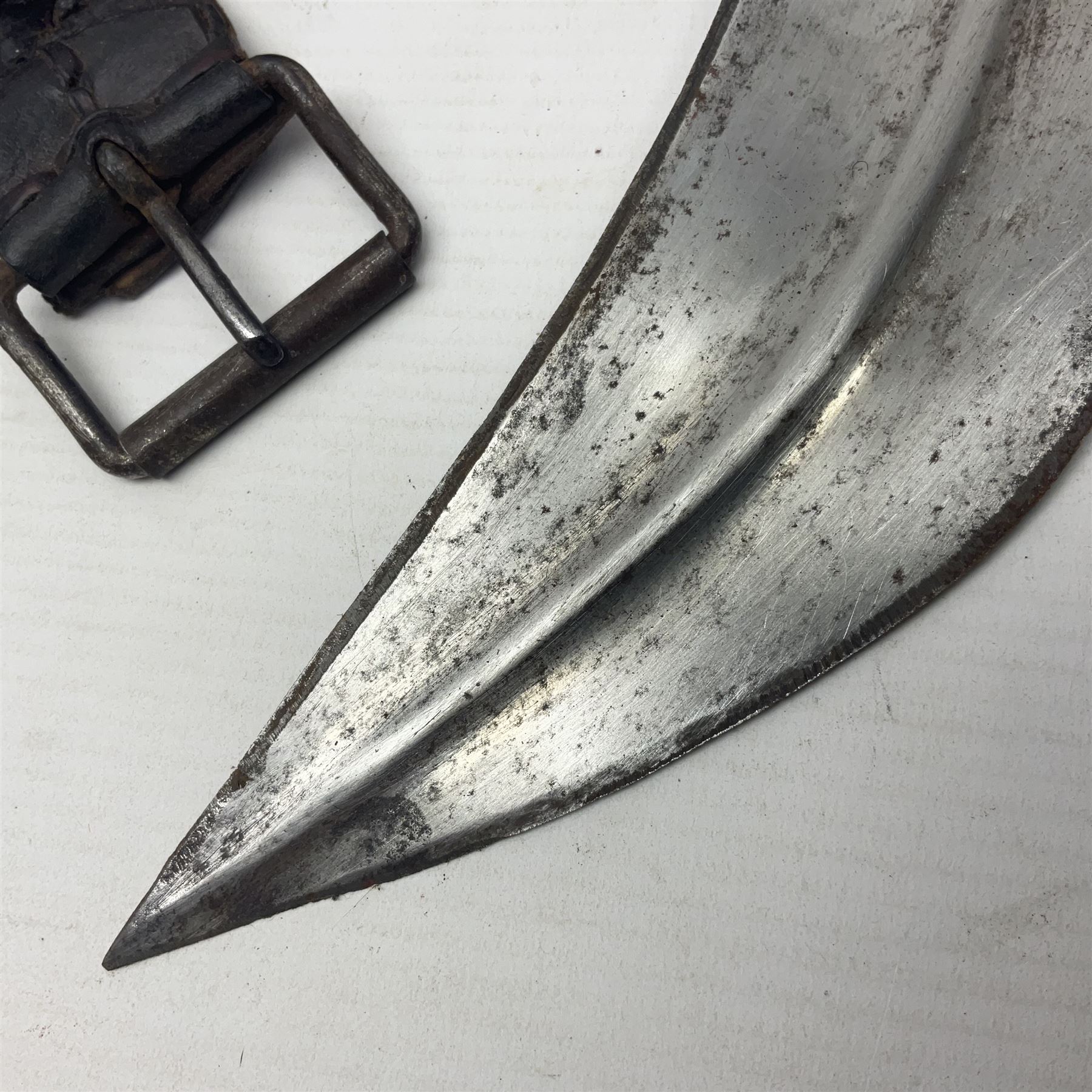 Eastern Jambiya, the 19cm double edge steel blade with raised medial ridge, waisted horn grip with pique work and white metal band; in stitched leather scabbard L33cm overall
