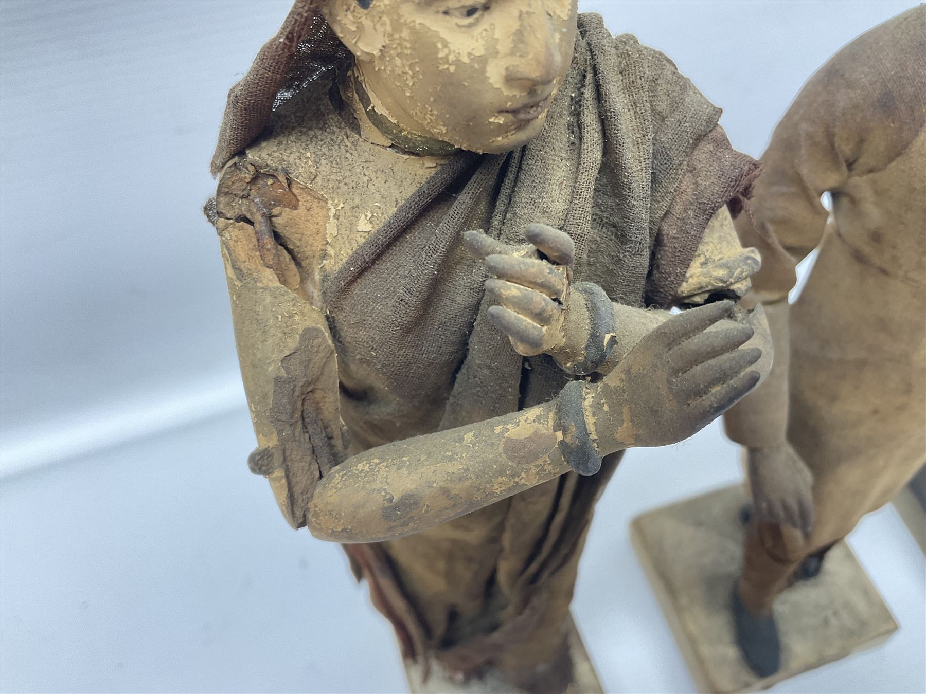 Seven 19th Century Indian clay dolls, possibly Krishnanagar, each figure with painted details, wearing cloth garments, standing on rectangular bases, some with paper label to the base, H25cm