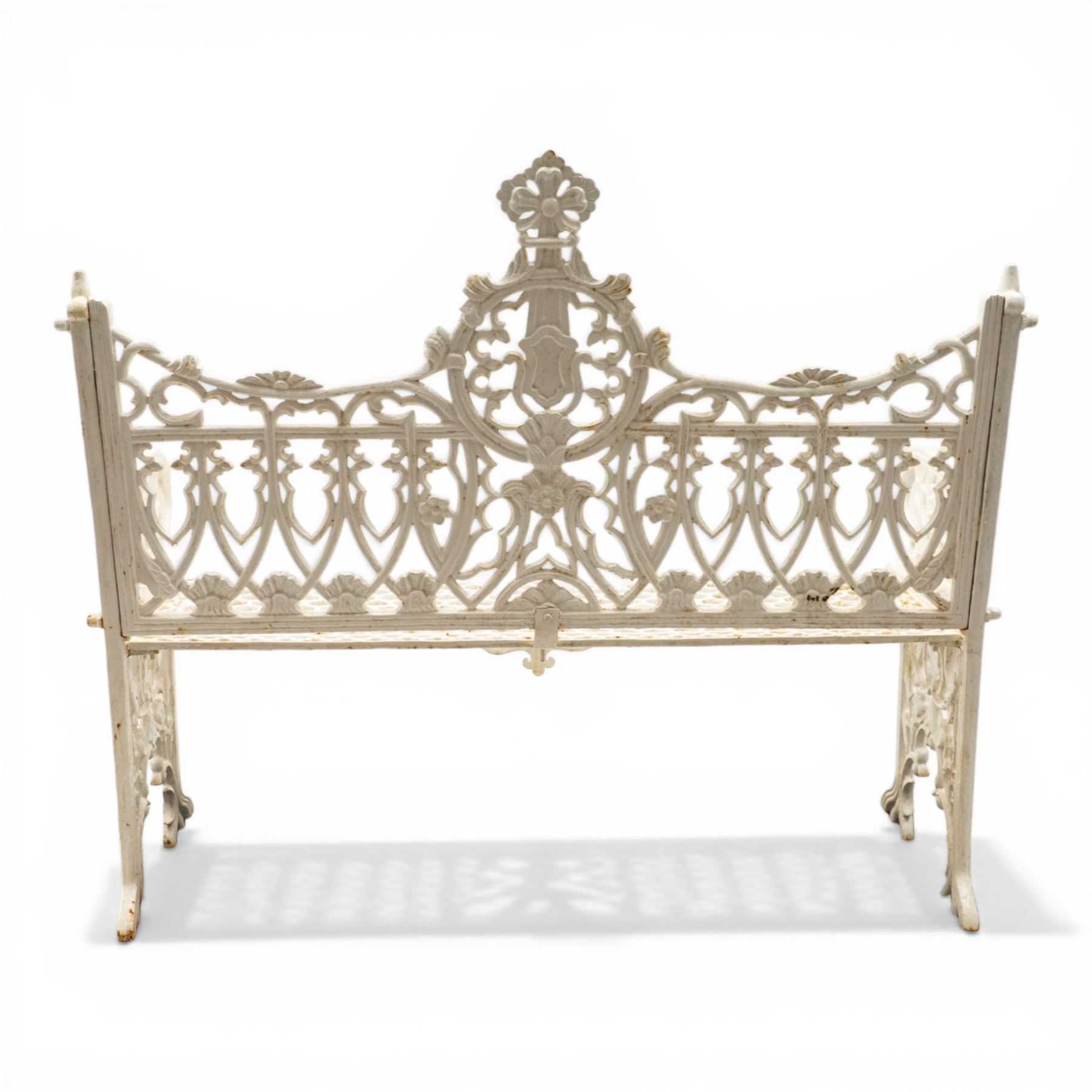 Victorian revival heavy cast iron garden bench, ornate back rest with scrolls, floral motifs and central crest, pierced lattice seat, curved arms and decorative legs, painted in antique white, in the Gothic Coalbrookdale style