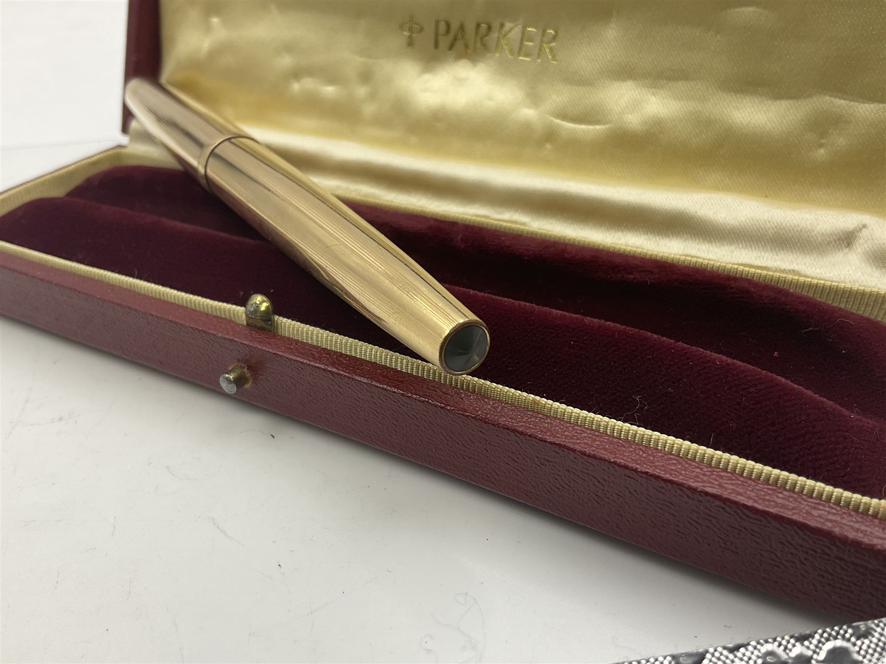 Three rolled gold Parker fountain pens, comprising an example with a gold nib marked 14K 585 and barrel with a shell stamp, a Parker 61 fountain pen with inset gold arrow to the nib, and another similar, all with striated decoration and arrow clips to the caps, L13cm, one with box