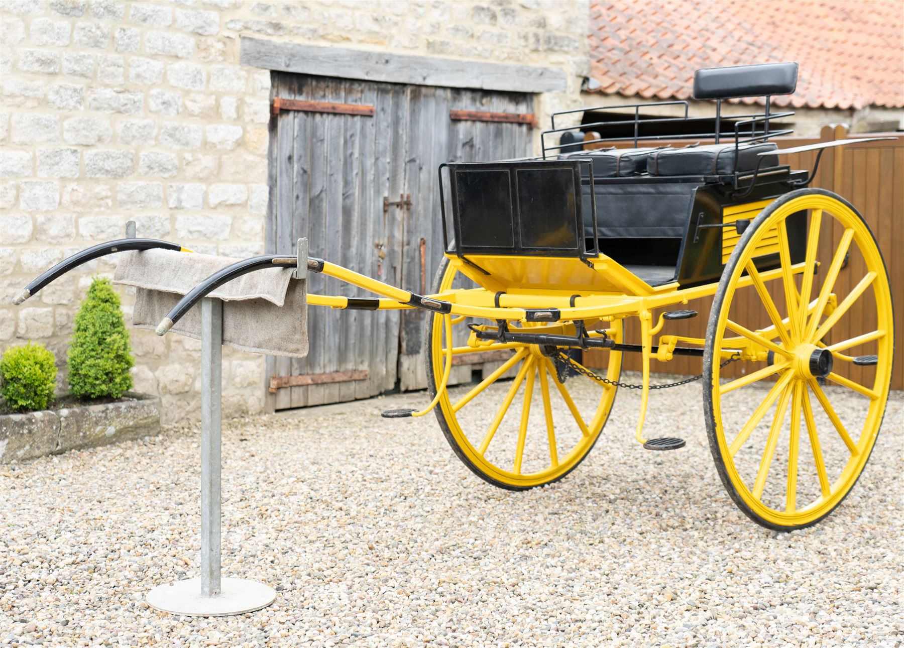 J. W. Thompson Dog Cart

A black and yellow painted two wheeled dog cart with elevated upholstered seat for two, buttoned black leather cushions, high back rail, folding front footboard, louvred sides, side steps, rear drop-down tailboard with chain stays, internal storage compartment, wooden spoked wheels, rubber tyres and shafts for a single horse. The wheel hubs are marked J W Thompson

Dimensions:
Overall length: 366 cm
Width: 160 cm
Height: 190 cm

Wheel Diameter:
Wheels: 139 cm

Seating:
Driver and passenger: 2