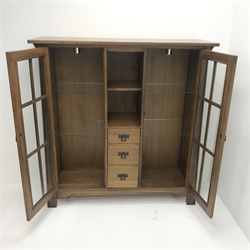  Arts & Crafts style oak cabinet, two glazed doors flanking single shelf and three graduating drawers, stile supports, W130cm, H134cm, D41cm  