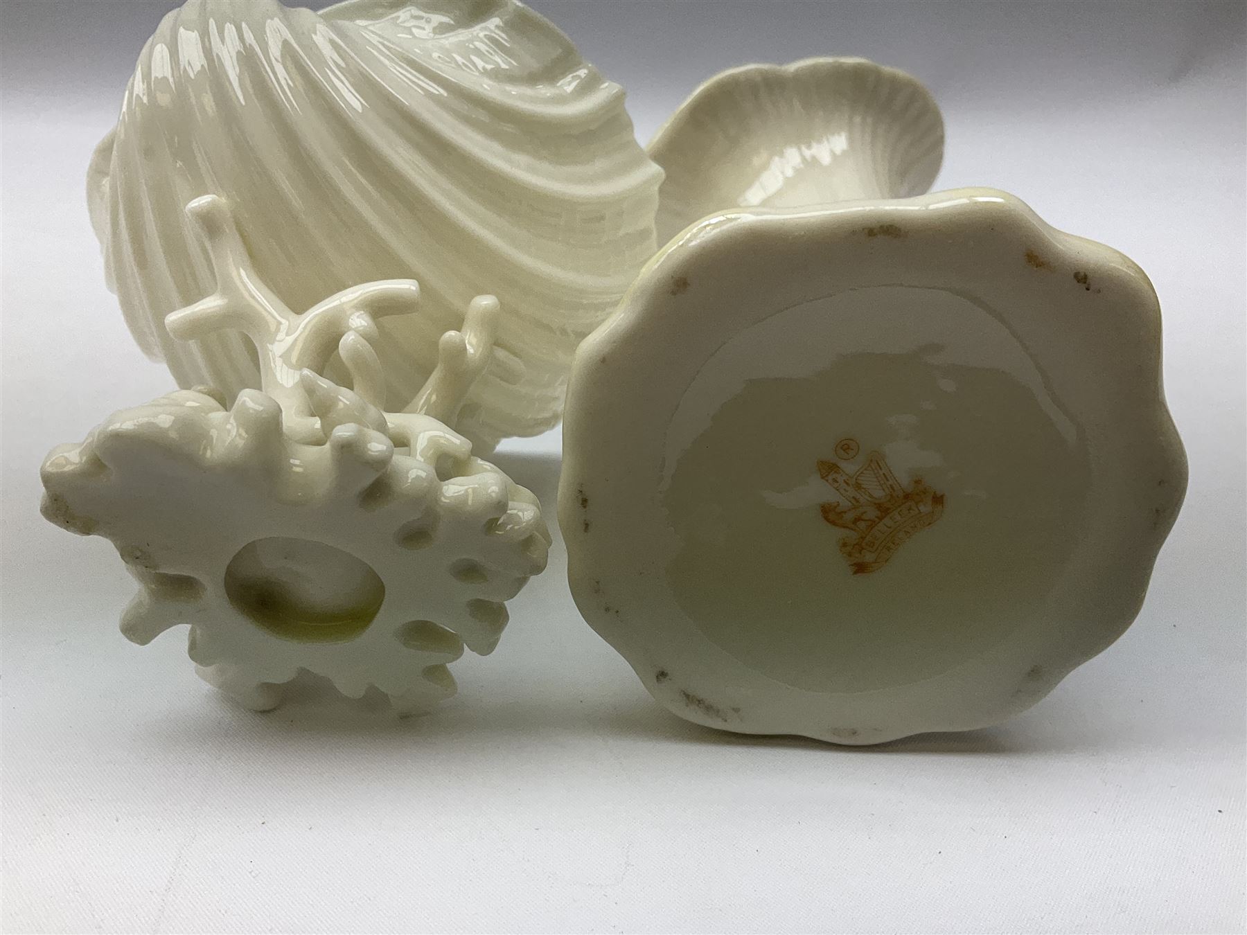 Quantity of Belleek ceramics to include mid-late 19th century jug moulded with green man mask and foliage, date code stamp for 1863-1890, together with later Belleek cornucopia shape vase, jug and other vases together with a Belleek style shell dish raised on branches, tallest H19cm