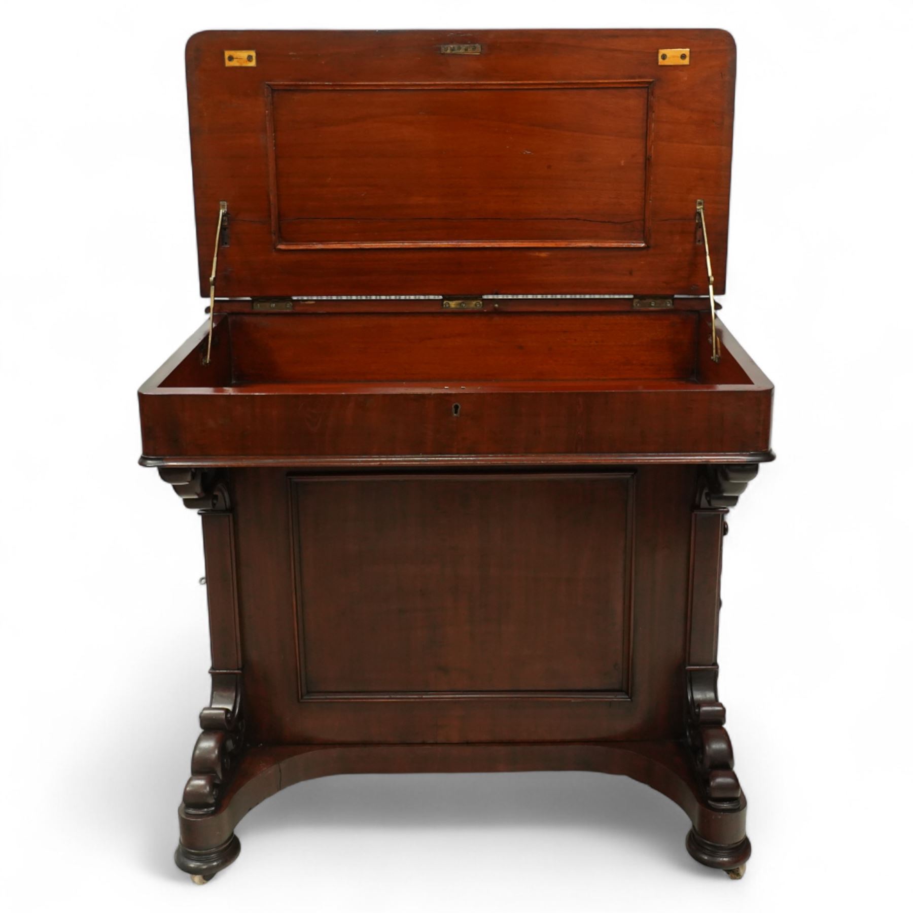 Large Victorian mahogany Davenport, the sloped leather inset writing surface opening to reveal fitted interior, with four drawers to one side and opposing dummy front cupboard door, carved scrolled supports and panelled back, raised on turned feet with brass castors 